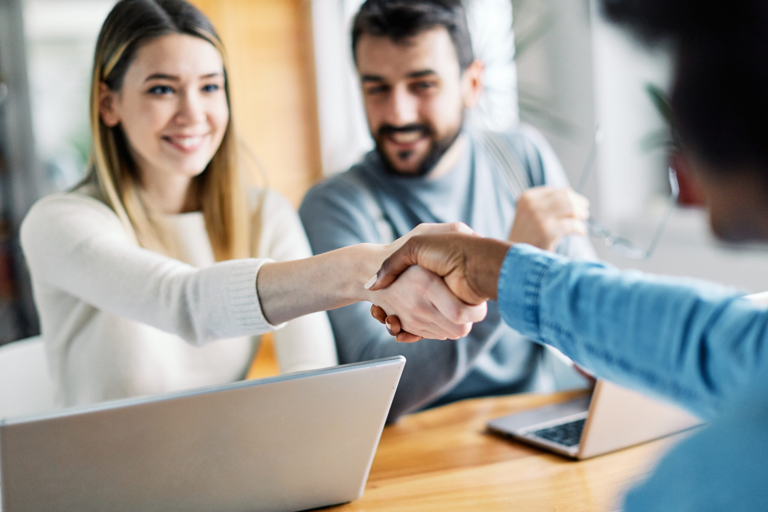 Real estate agent with couple shaking hands closing a deal